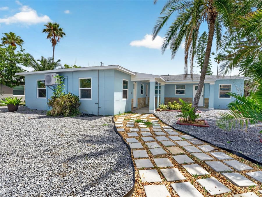 Light-blue coastal home with paver walkway in Madeira Beach